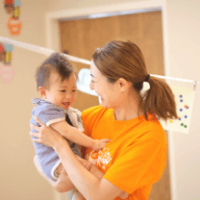 笑顔の子どもを抱き抱える保育士